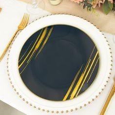 a black and gold dinner plate on a white table cloth with flowers in the background