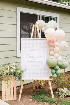 a welcome sign with balloons in front of a house