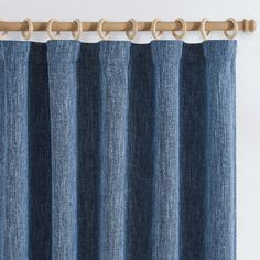 the blue curtain is hanging on the rod with wooden handles and two rings at the top