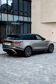 a silver range rover parked in front of a building on a cobblestone street