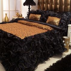 a bed with black ruffled bedspread and gold pillows on top of it