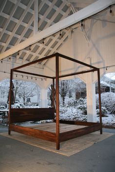 a canopy bed sitting in the middle of a covered patio with snow on the ground