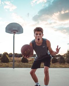 a young man holding a basketball on top of a basketball court in front of a hoop