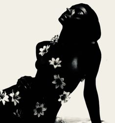 a black and white photo of a woman with flowers on her body