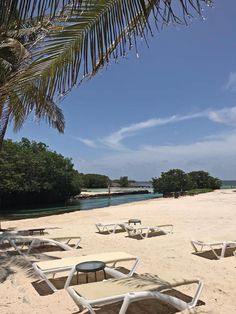 chairs and tables are set up on the sandy beach near the water's edge