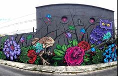 a mural on the side of a building with flowers and an owl painted on it