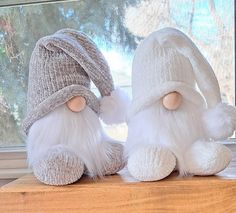 two white stuffed animals sitting on top of a wooden table next to a window sill