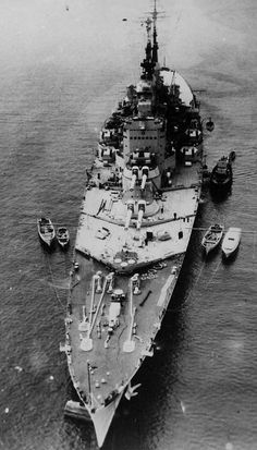 an old photo of a large ship in the water with smaller boats around it on the side