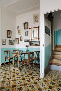 a dining room table and chairs with pictures on the wall behind them in an old house