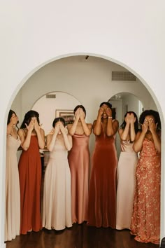 a group of women standing next to each other holding their hands up in front of their eyes