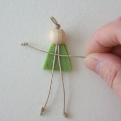 a hand holding a piece of string with a small green object attached to it