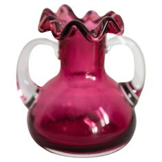 a pink glass vase sitting on top of a white table