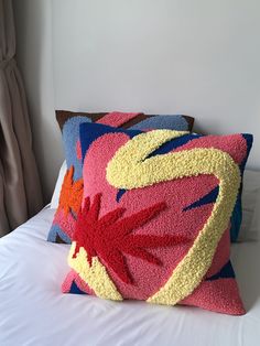 a colorful pillow sitting on top of a white bed