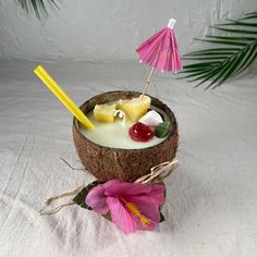 a drink in a coconut shell with fruit and an umbrella