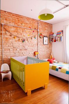 a child's room with a brick wall and green crib in the corner