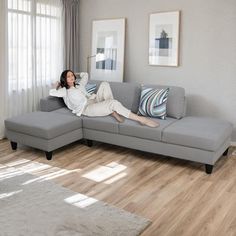 a woman laying on top of a gray couch