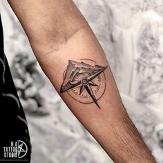 a man's arm with a compass and mountains tattoo on the left inner forearm