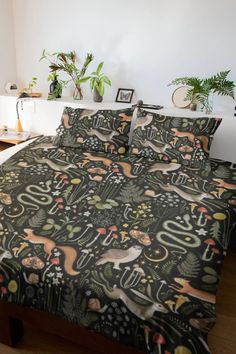 a bed covered in a black and green comforter next to a plant filled wall