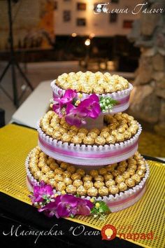 three tiered wedding cake with flowers on the top and bottom, sitting on a yellow tablecloth