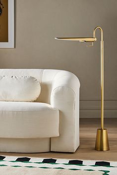 a white couch sitting next to a lamp on top of a hard wood floor in a living room