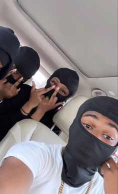 three women wearing black masks sitting in the back of a car