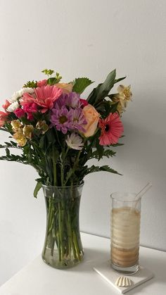 a vase filled with lots of flowers next to a drink