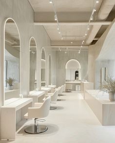 the interior of a hair salon with white chairs and mirrors on either side of the room