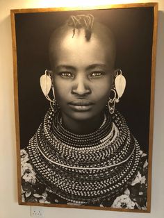 a black and white photo of a woman with large earrings on her head in front of a wall