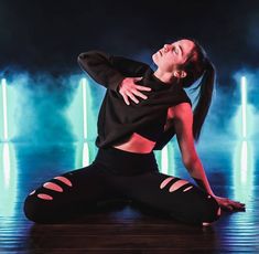 a woman is sitting on the floor with her arms stretched out in front of her