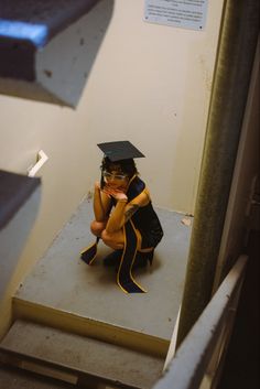 a person sitting on top of a step wearing a graduation cap and gown