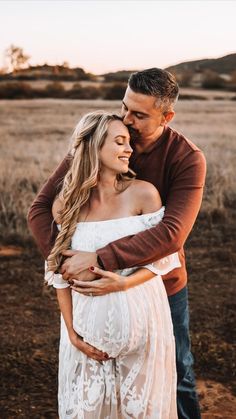 a man and woman embracing each other while standing in the middle of an open field