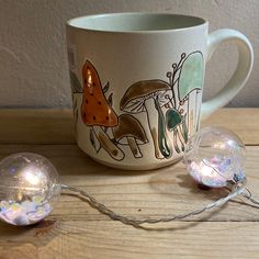 a coffee cup sitting on top of a wooden table next to two disco ball lights