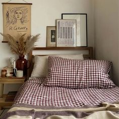 a bed with plaid sheets and pillows in a bedroom next to pictures on the wall