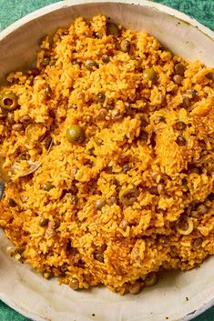 a bowl filled with rice and olives on top of a green tablecloth covered floor