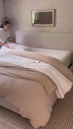 a woman in white shirt laying on top of a bed next to a wall mounted mirror