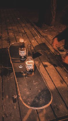 two bottles of beer are sitting on a skateboard