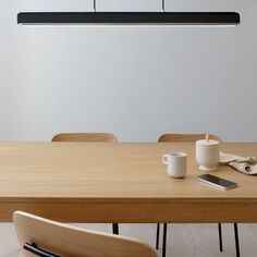 a wooden table with two cups on it next to a cell phone and other items