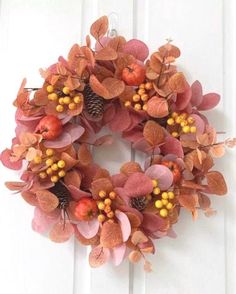 a wreath is hanging on the door with berries and leaves around it's edges