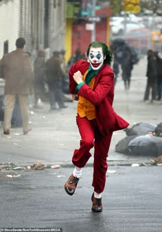 a man dressed as the joker is running in the street