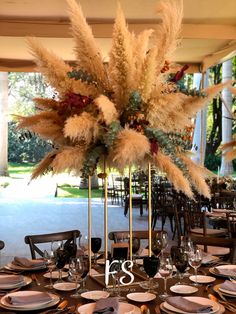 the table is set with plates, silverware and tall pamodia centerpiece