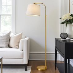 a living room with a white couch and a gold floor lamp