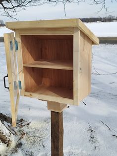 a wooden box sitting in the snow next to a tree