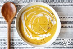 a white bowl filled with soup next to a wooden spoon on top of a table