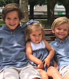 three children are sitting on a park bench