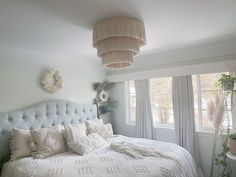 a white bed sitting next to a window in a room with lots of pillows on top of it