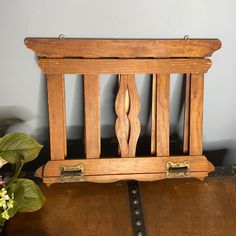 a wooden bench with metal handles on top of a brown leather floor next to a potted plant