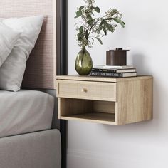 a bedside table with a vase and books on it