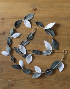 some white and black leaves are on a wooden table with string attached to it's sides