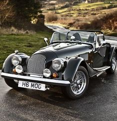 an old black car is parked on the side of the road