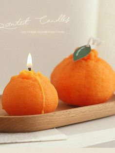 two oranges sitting on top of a wooden tray with a candle in the middle